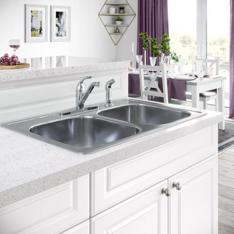 A white kitchen with a silver sink and faucet